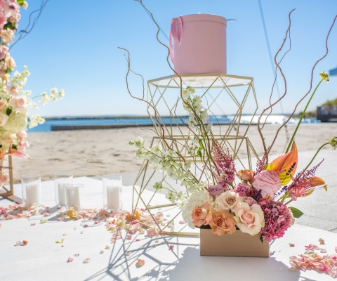 Part of the wedding arch decorated with fresh flowers is set on the sandy bank of the river. Wedding florist arranges workflow